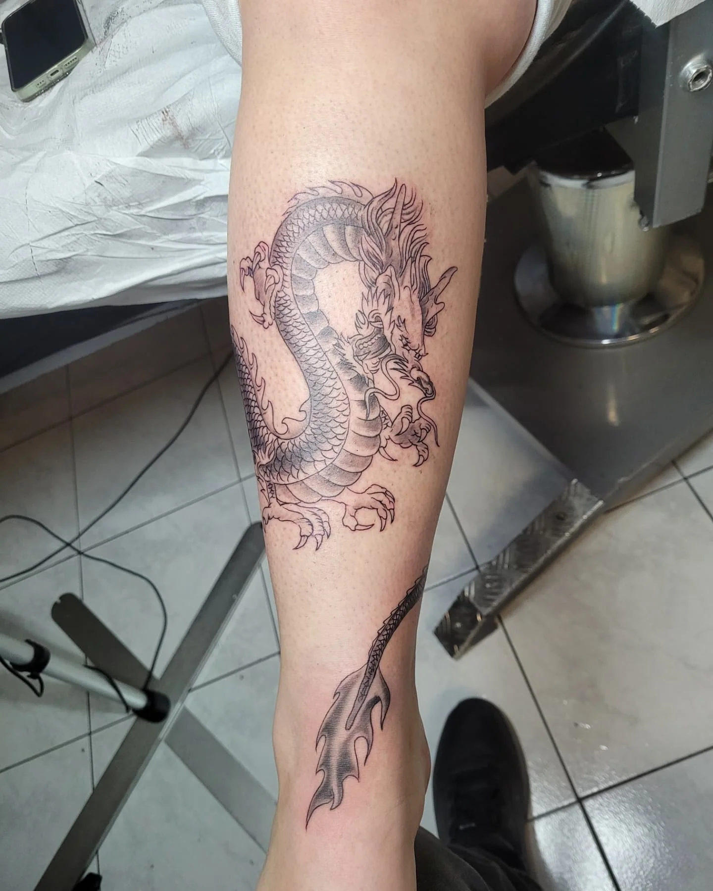 Tatouage japonais d'un dragon enroulé sur le mollet, lignes noires fines et écailles détaillées, réalisé par Jean-Marie Joullié au salon JMJ Tattoo à Béziers et Sérignan